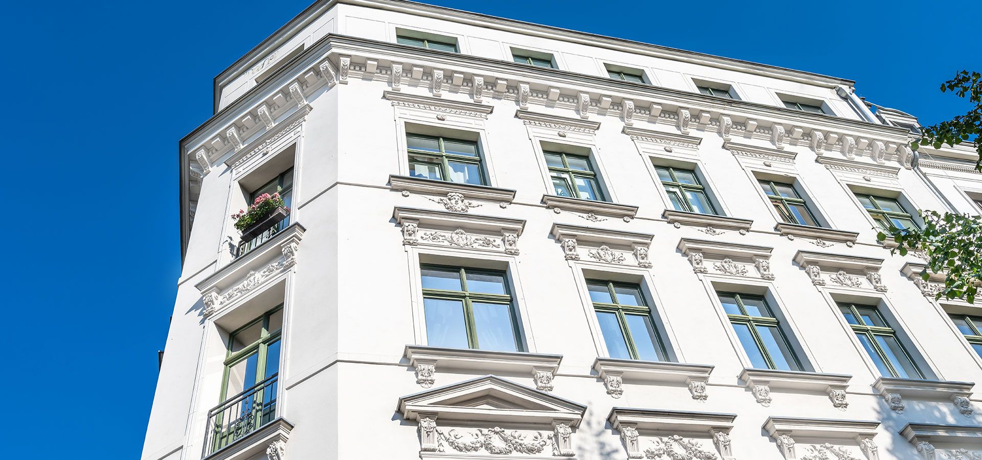 Helles Wohngebäude mit Verzierungen über den Fenstern